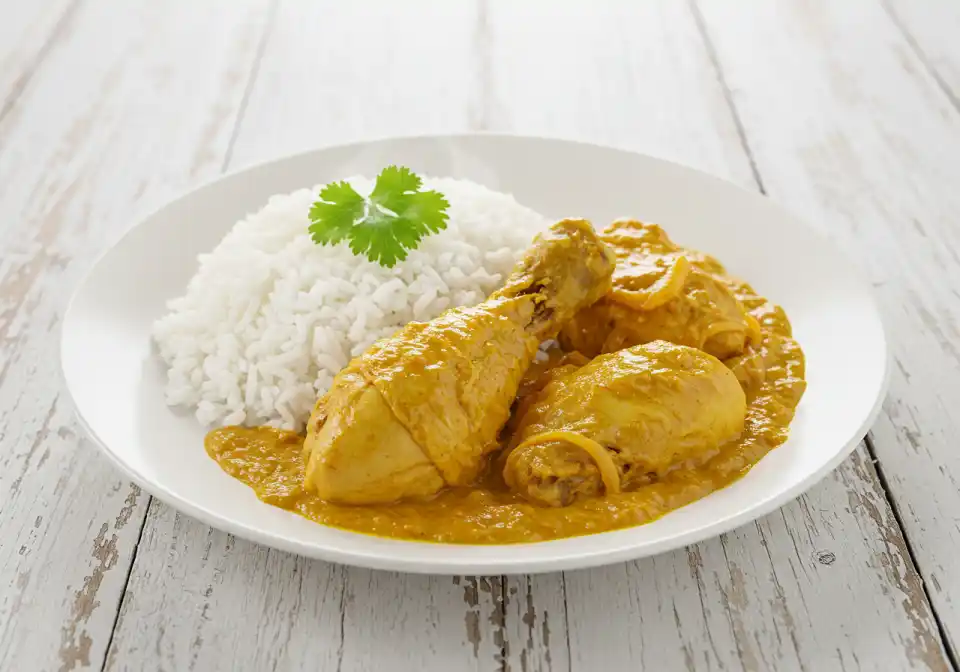 Churu Chicken Amarillo: A close-up shot featuring golden chicken drumsticks covered in orange Amarillo sauce next to a cup of white rice.