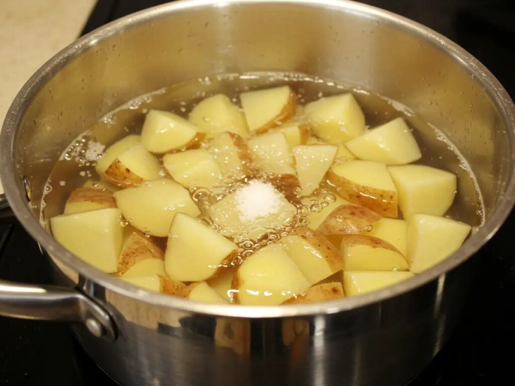 Chopped potatoes with skin on boiling in water with salt, to make the base for chicken noodle soup over mashed potatoes.