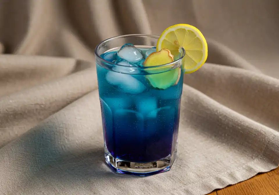 Ready-to-drink Brazilian Mounjaro recipe detox beverage in clear glass with ice, lemon wedge, and ginger slice, placed on beige linen cloth