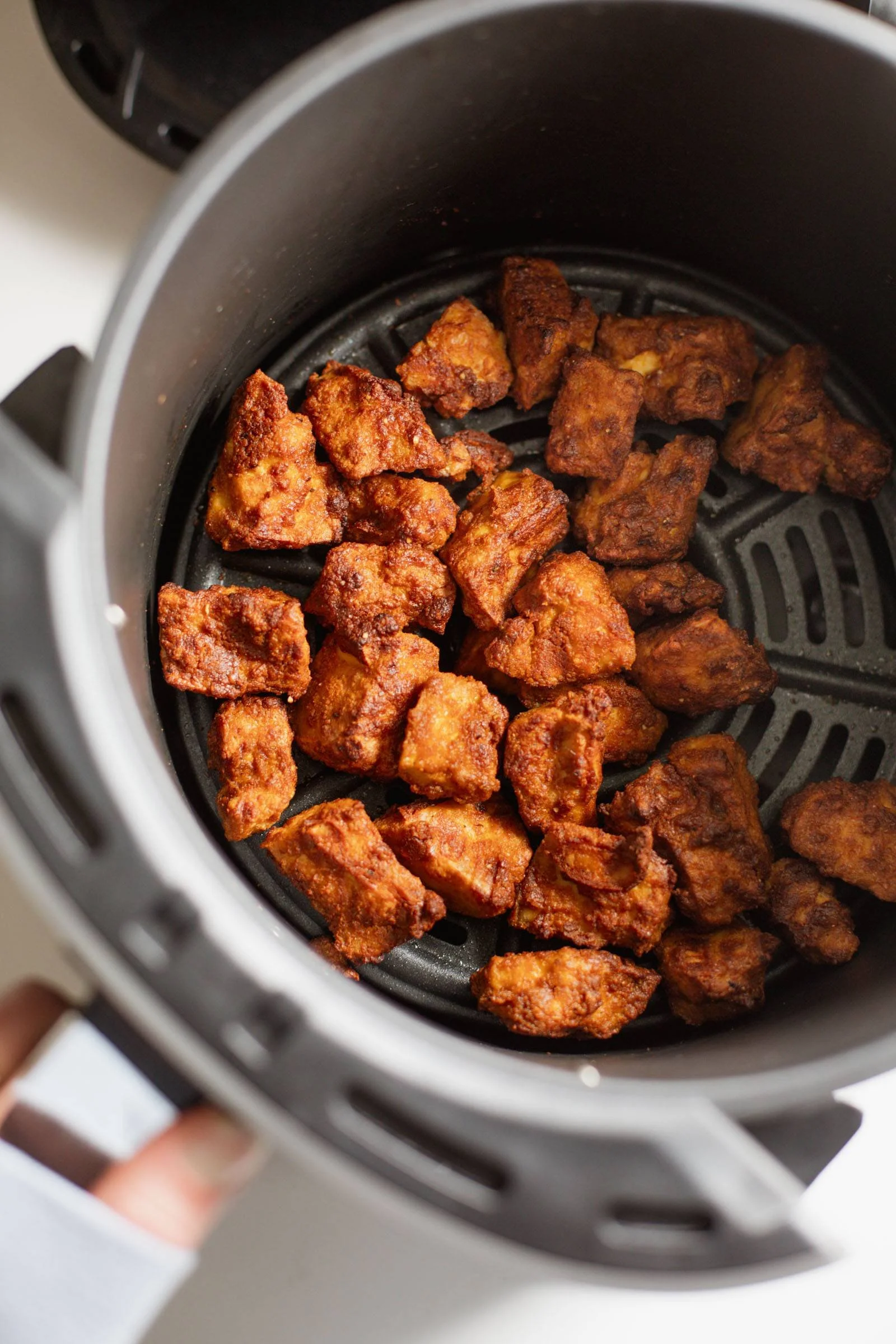Crispy air fryer tofu on a plate garnished with herbs.
