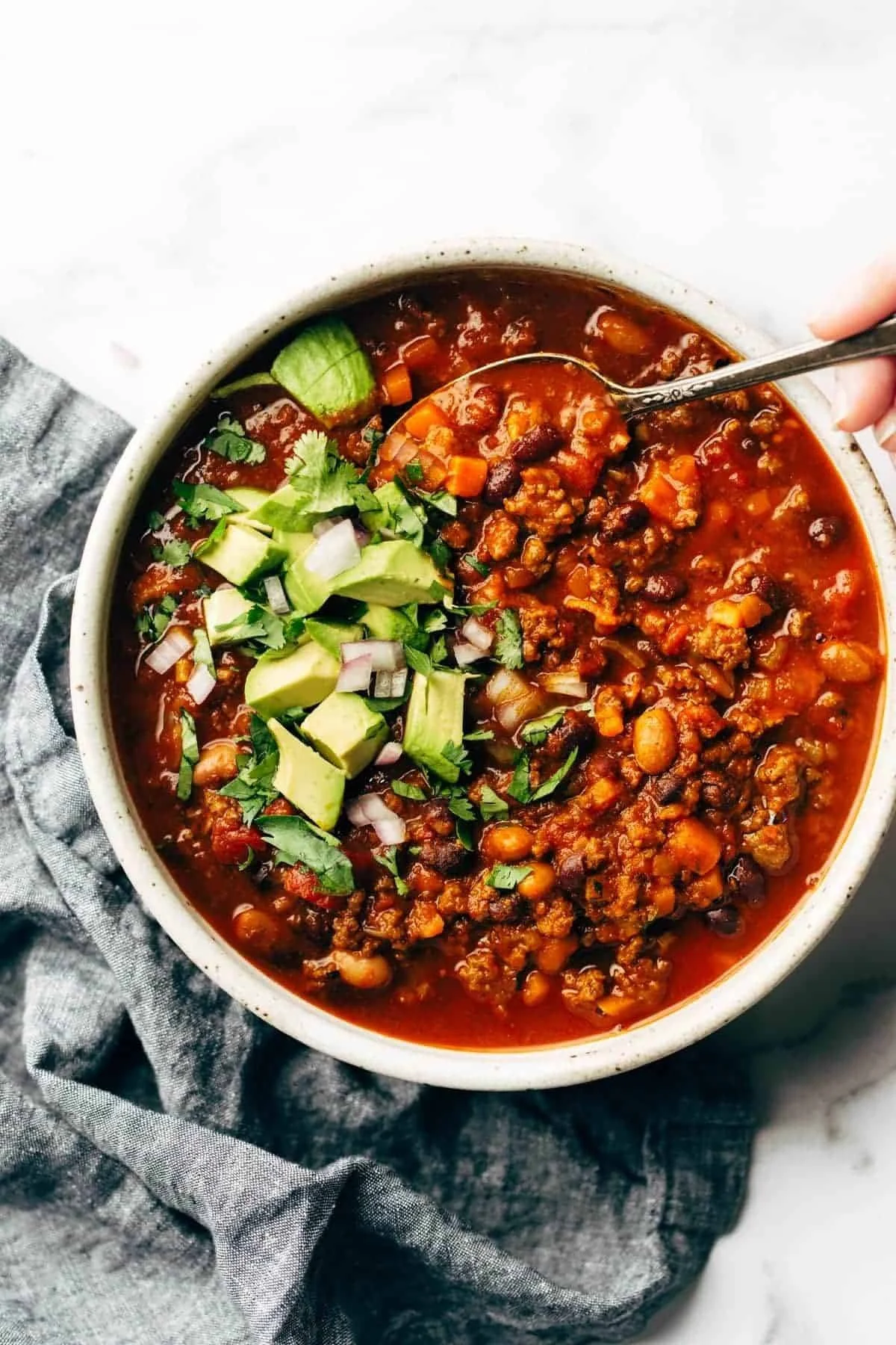 A bowl of the best Sunday chili topped with cheese and cilantro.