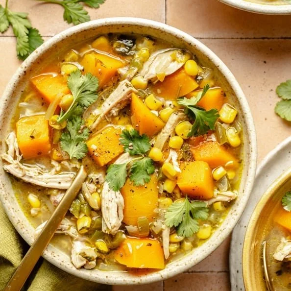 Bowl of Butternut Squash Green Chile Chicken Soup garnished with fresh herbs