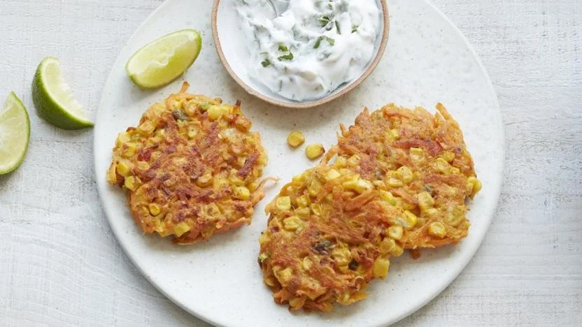 Carrot and sweetcorn fritters served on a plate with herbs