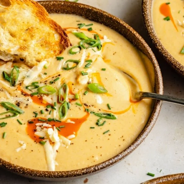 Bowl of Cheddar Buffalo Cauliflower Soup garnished with green onions.