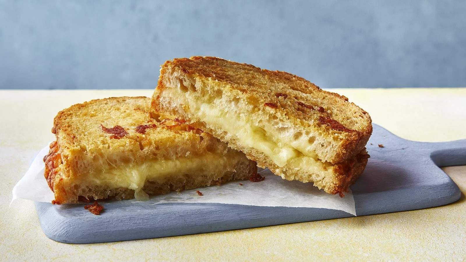 Delicious cheese toastie with pickles on a wooden board.