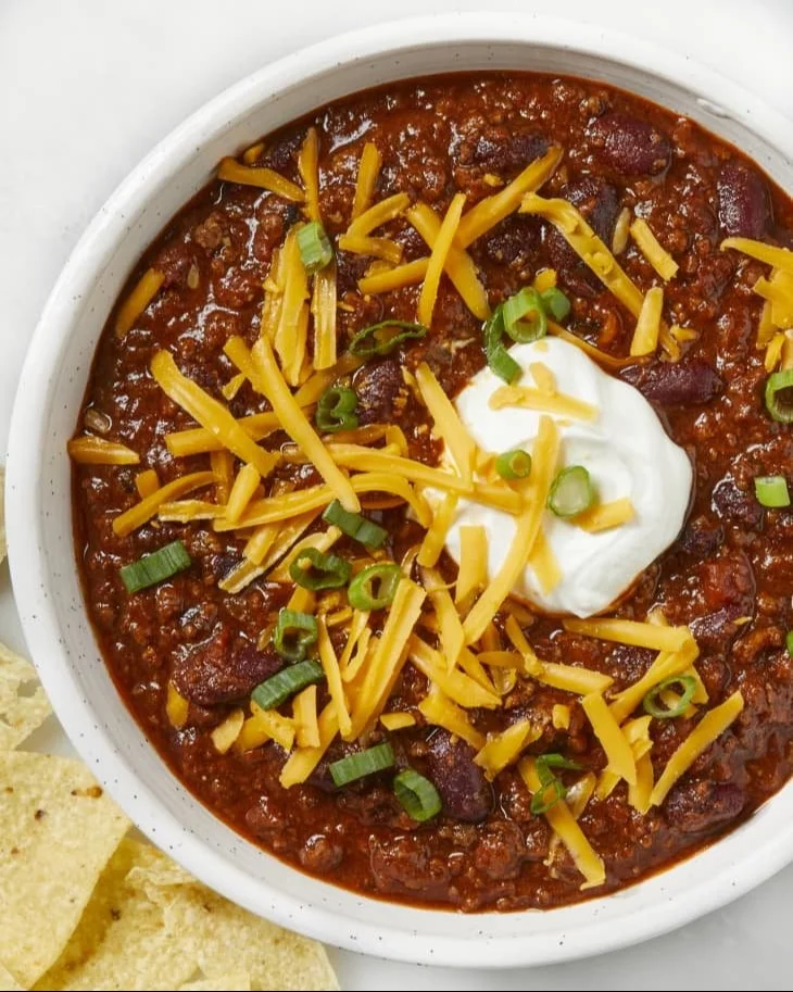 Bowl of classic beef chili topped with cheese and herbs