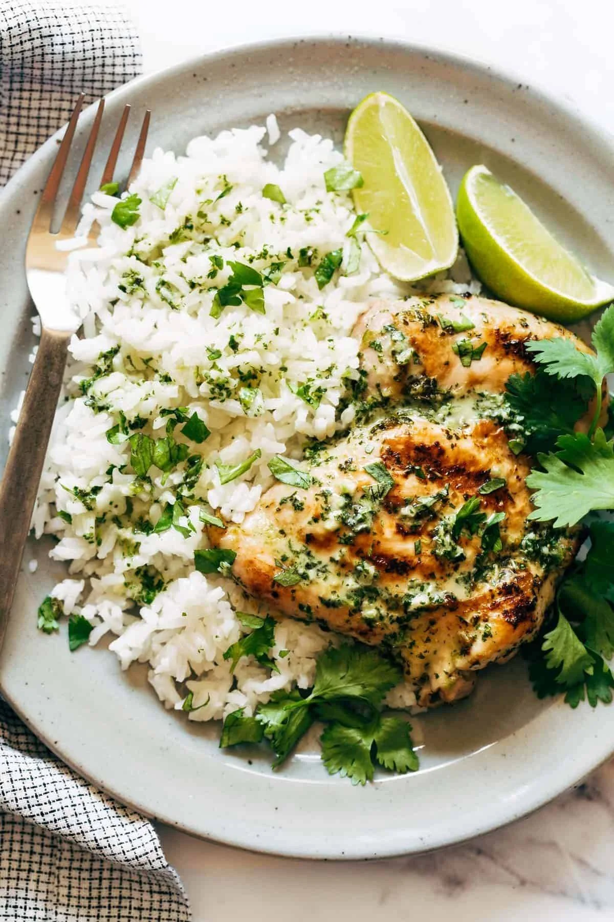 Coconut Lime Grilled Chicken served on a plate with rice and fresh lime garnishes.