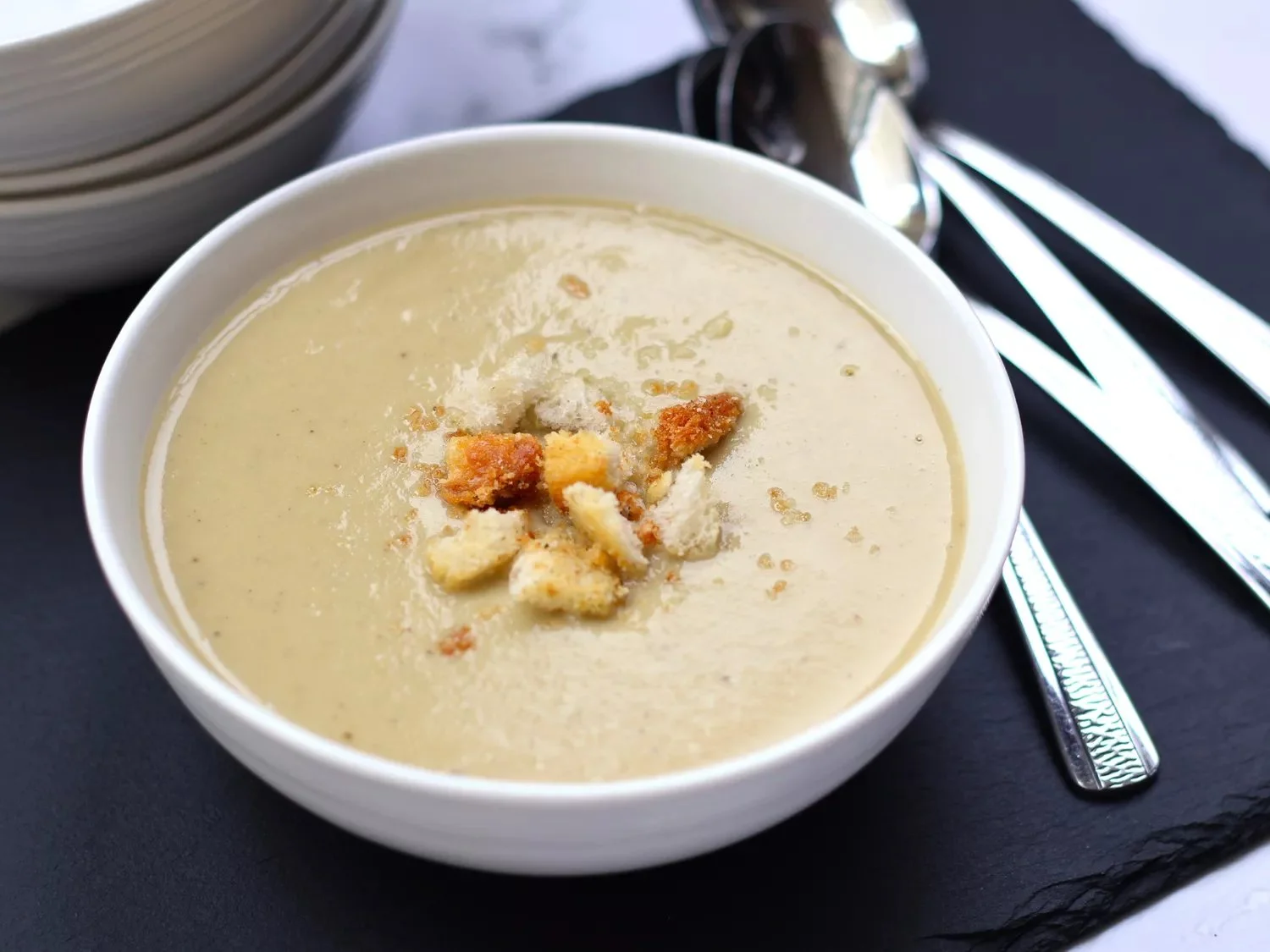 Delicious bowl of cream of artichoke soup garnished with fresh herbs