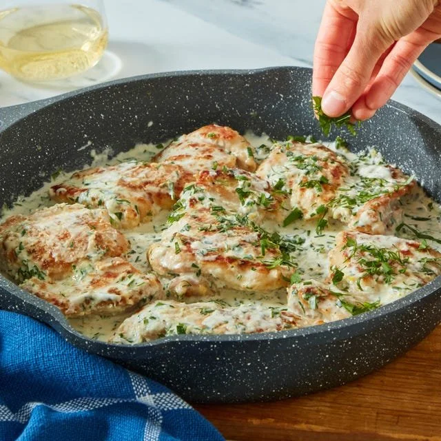 Creamy lemon herb chicken served on a plate with fresh herbs and lemon slices.