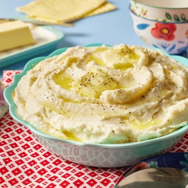 Creamy mashed potatoes served in a bowl with butter and herbs on top