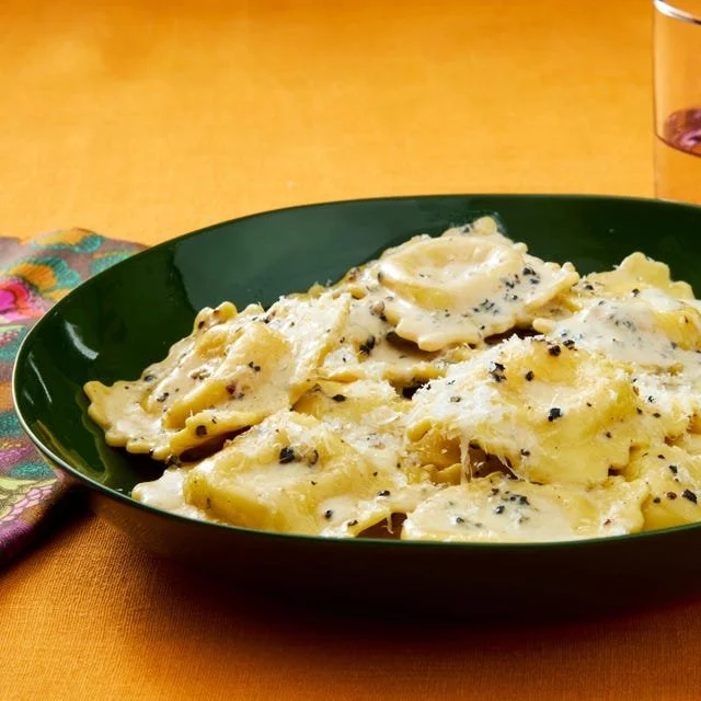 Plate of creamy peppery cheese ravioli garnished with fresh herbs