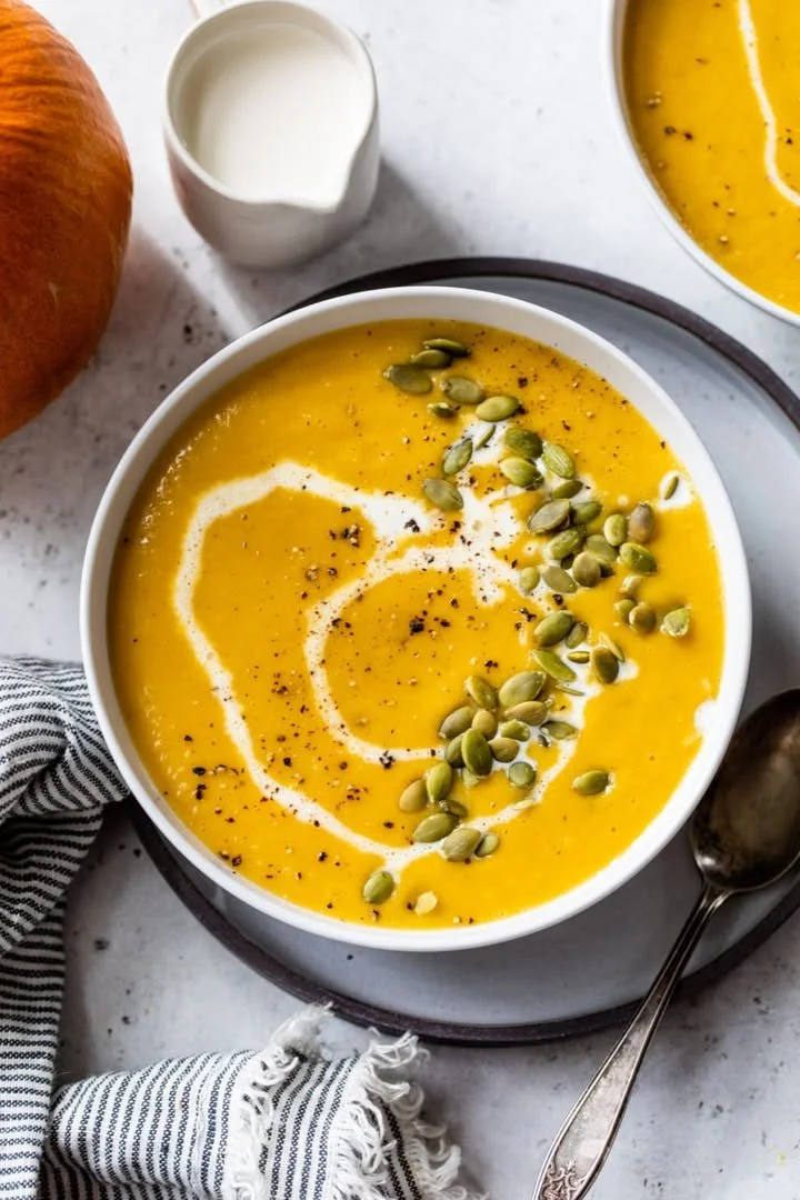 Delicious creamy pumpkin soup served in a bowl with parsley garnish.