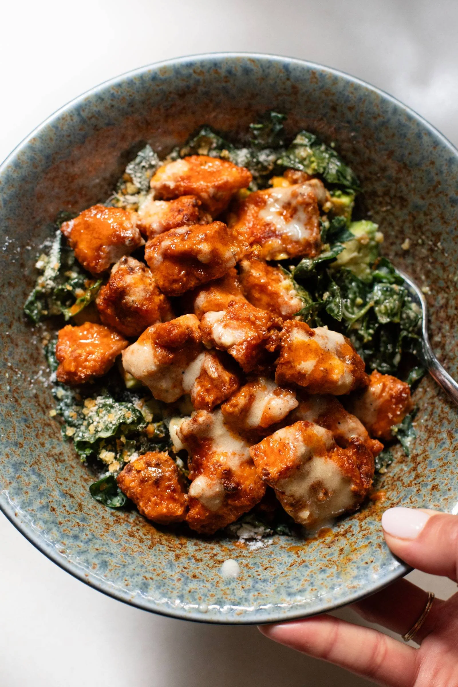 Plate of crispy buffalo tofu served with Caesar salad.