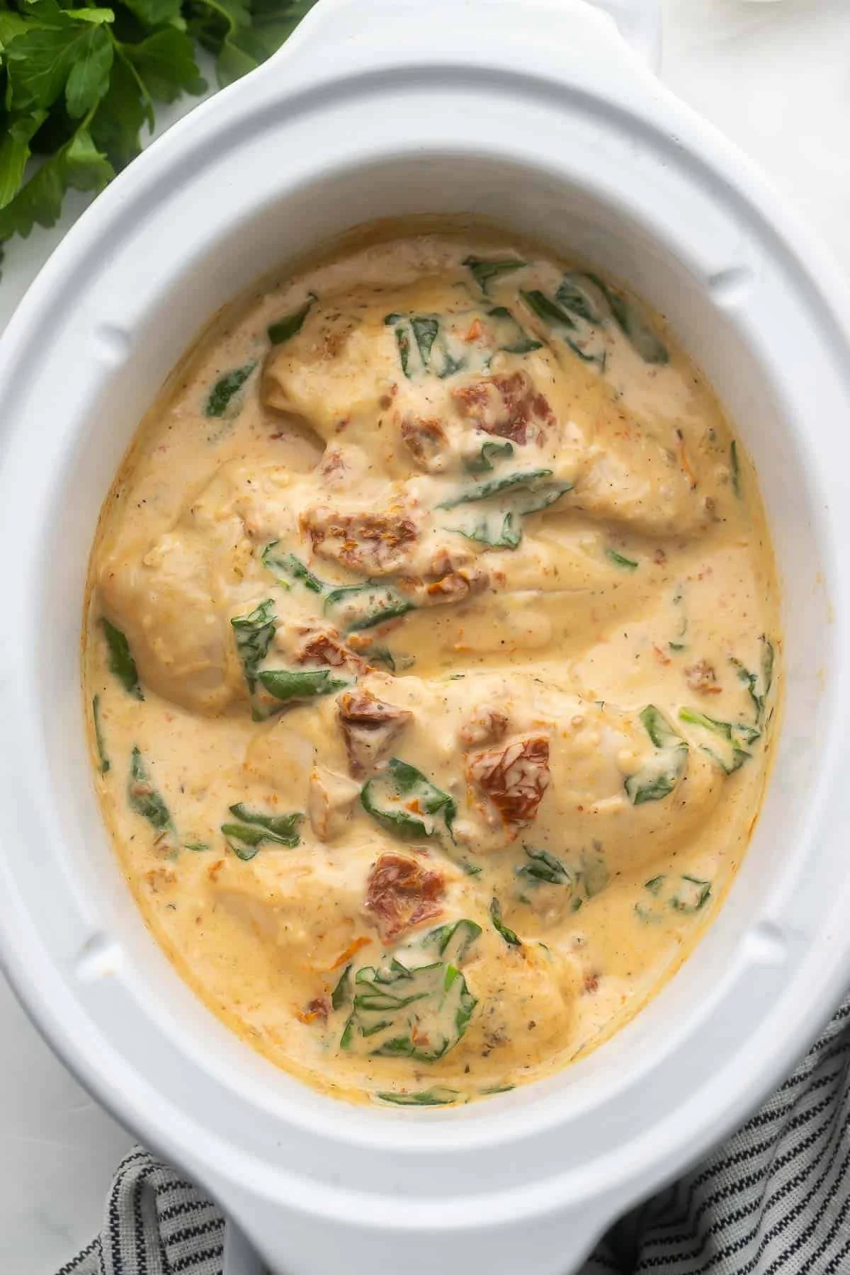 Delicious Crockpot Tuscan Chicken served with herbs and vegetables.