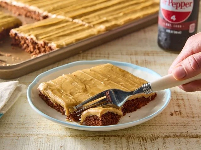 Delicious Dr Pepper Sheet Cake with chocolate frosting on a white plate.