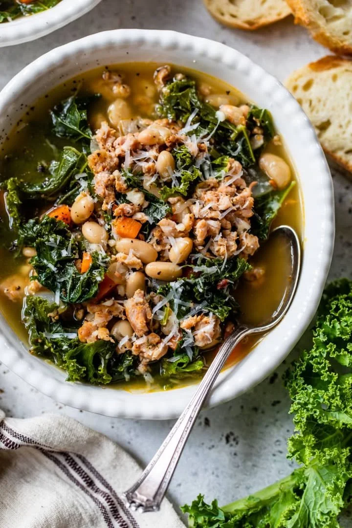 Bowl of easy kale soup garnished with fresh herbs and served in a rustic bowl