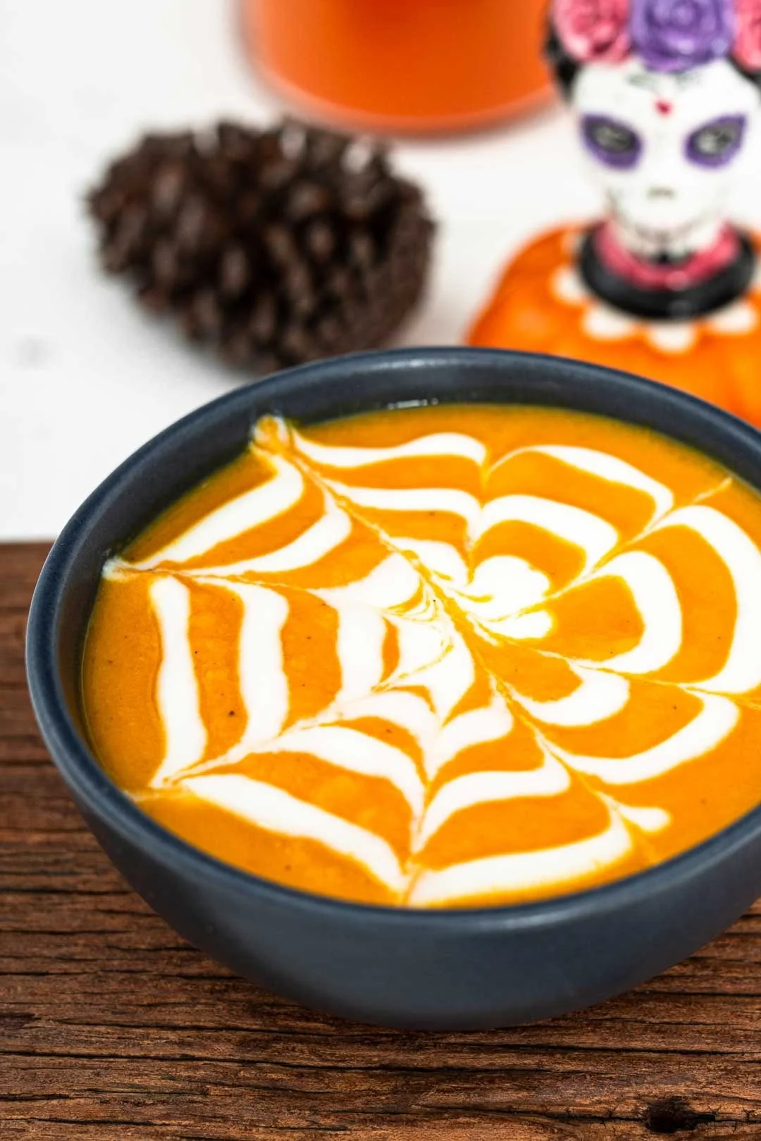 Halloween carrot soup served in a pumpkin bowl, garnished with herbs
