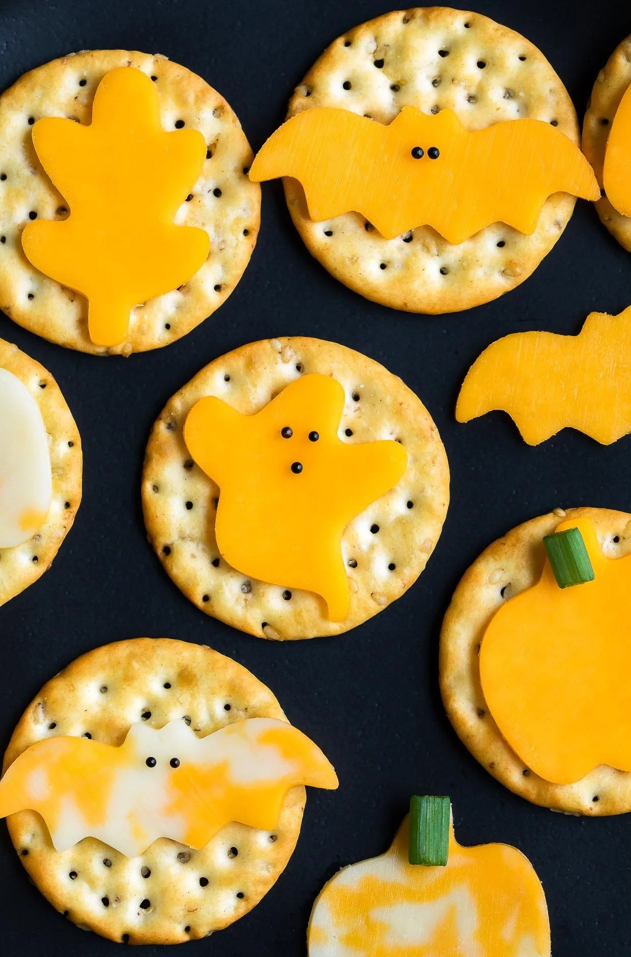 Festive Halloween cheese and crackers platter with spooky decorations and flavors.