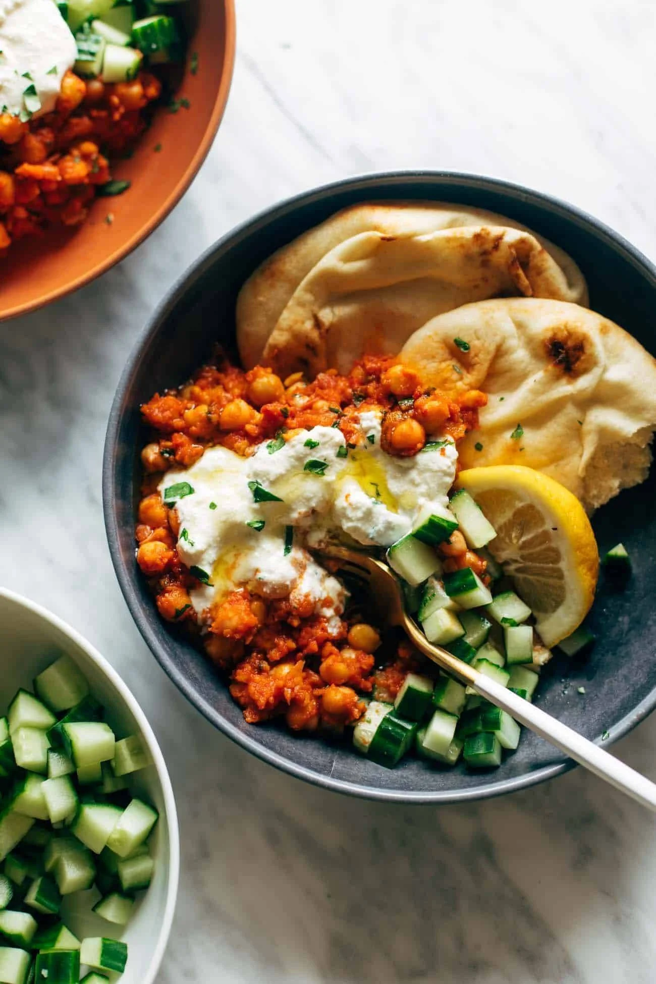 Plate of harissa chickpeas garnished with whipped feta and herbs.