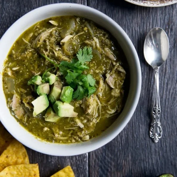 Healthy slow cooker chicken green chile dish in a bowl with fresh toppings