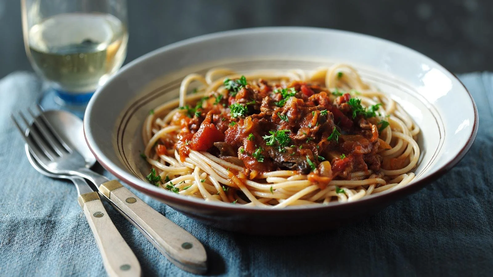 Healthy spaghetti bolognese served in a bowl with fresh basil and parmesan cheese