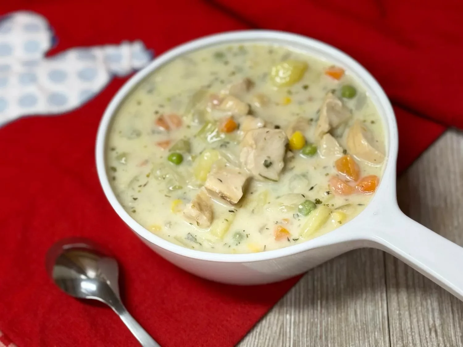 Bowls of creamy chicken vegetable soup with fresh vegetables and herbs