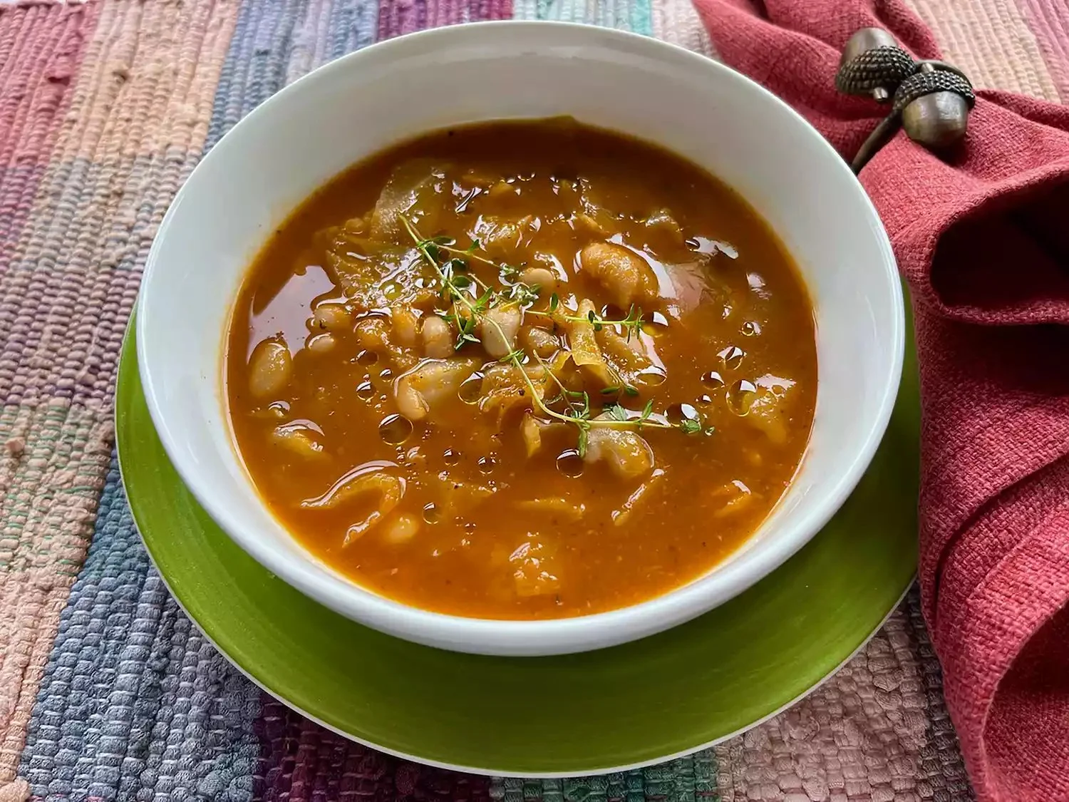 Bowl of hearty cabbage bean soup with fresh herbs and vegetables.