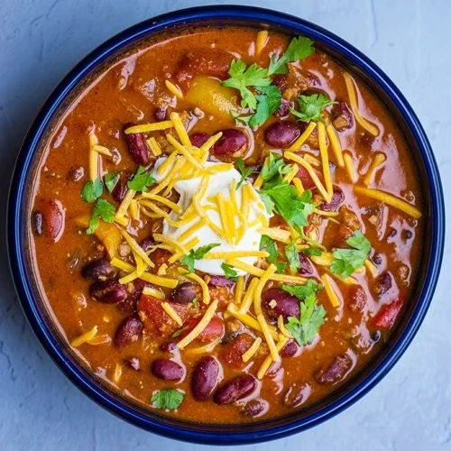 Bowl of hearty traditional chili garnished with fresh herbs