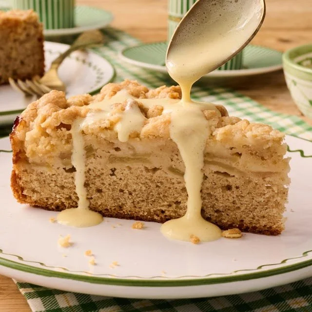 Irish Apple Cake topped with cinnamon and fresh apple slices on a wooden table
