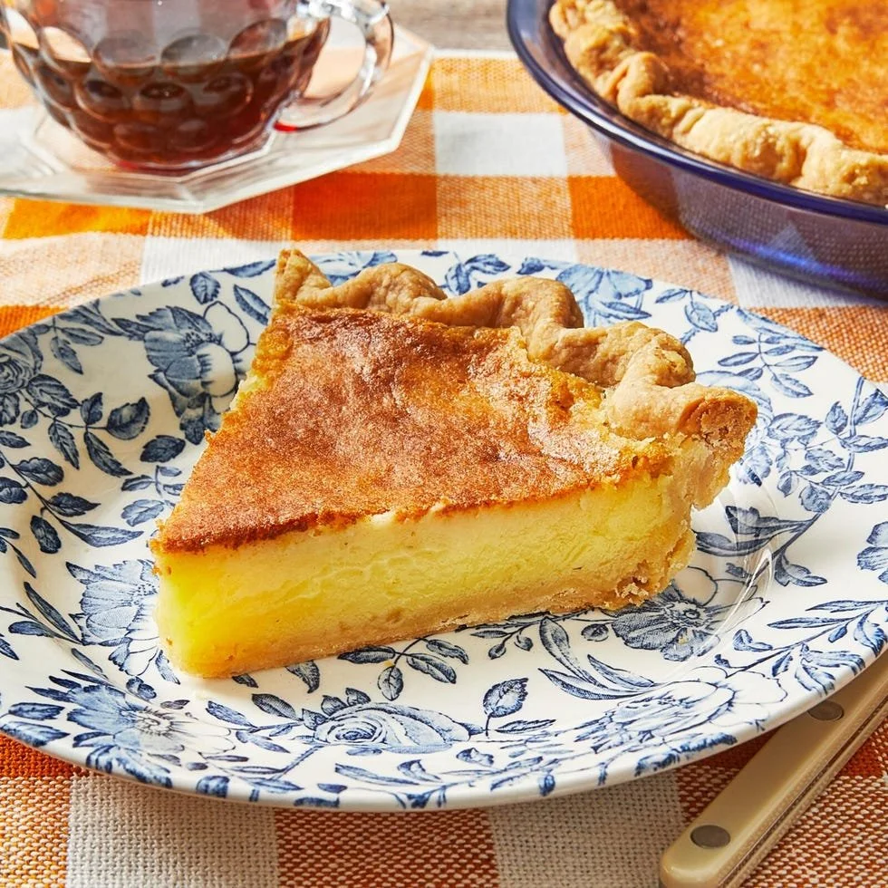 Delicious slice of Lemon Buttermilk Pie topped with whipped cream on a plate.