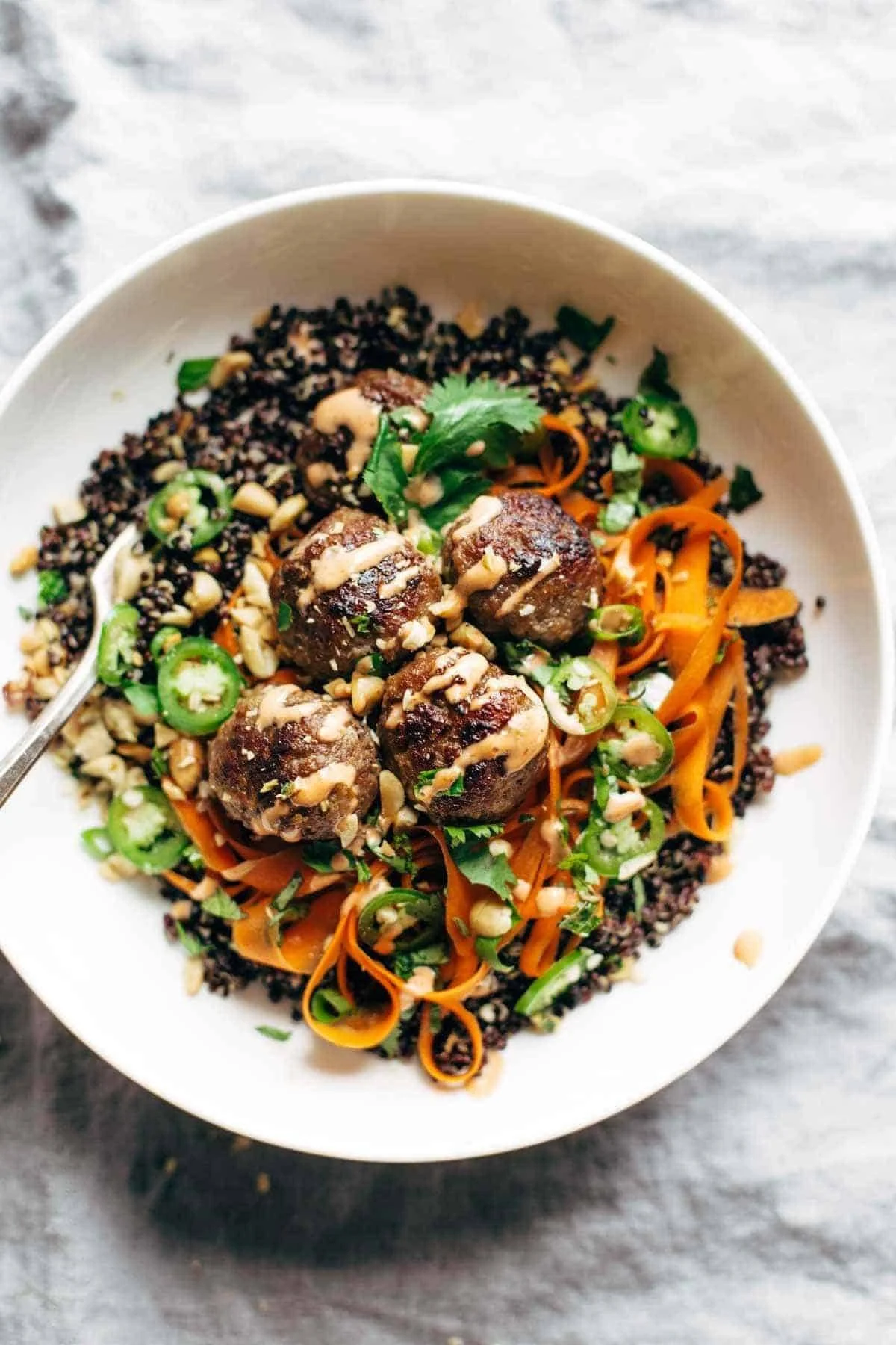 Bowl of lemongrass meatballs served with fresh herbs and rice