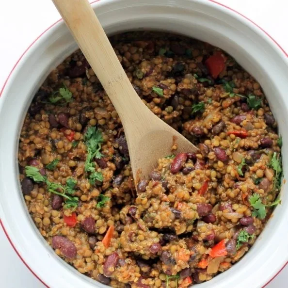 Bowl of hearty lentil quinoa chili topped with fresh herbs