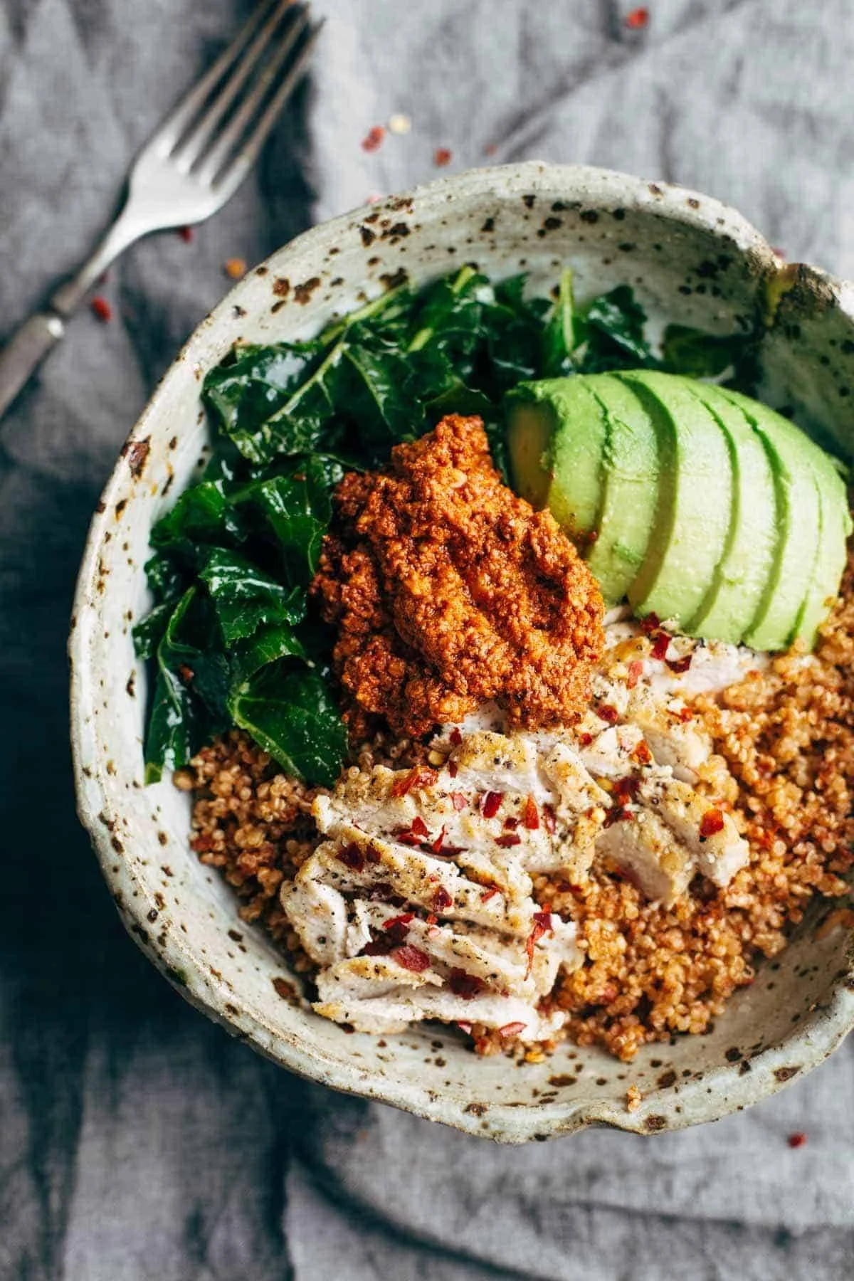 Marinated kale chicken bowl with sun-dried tomato sauce on a wooden table