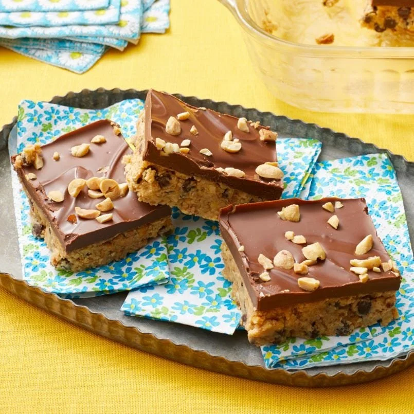 No-bake peanut butter bars stacked on a plate with a drizzle of chocolate