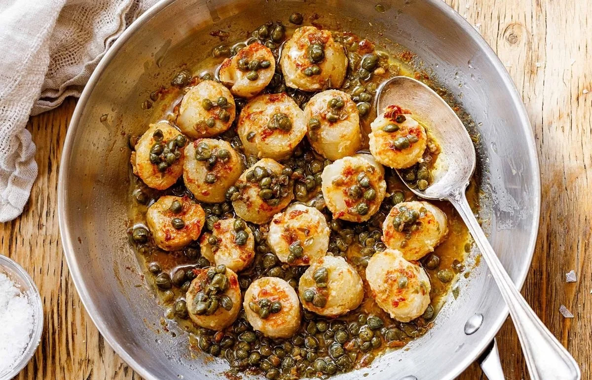 Pan seared sea scallops served with caper butter sauce on a plate