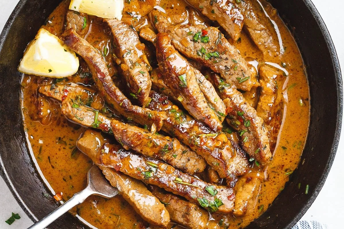 Pan-seared steak in rich butter sauce served on a plate.