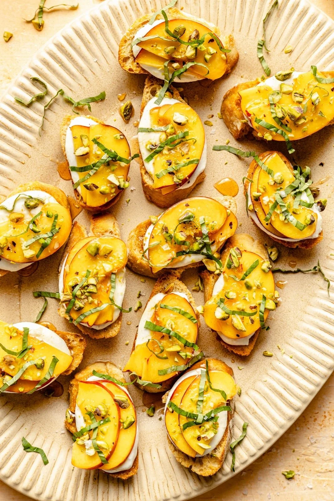 Peach Crostini with whipped cottage cheese, basil, and hot honey on a platter.