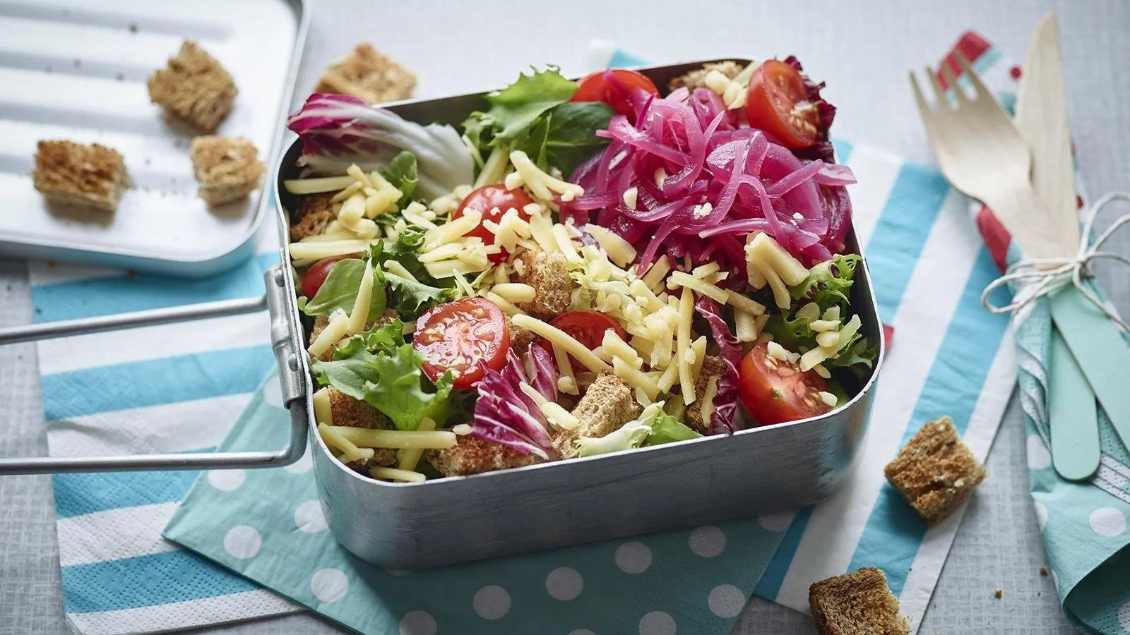 A vibrant Ploughman's lunch salad featuring cheese, bread, and fresh vegetables.