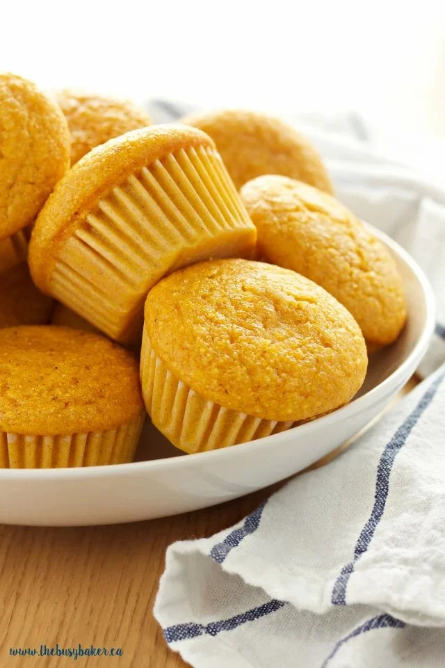 Freshly baked pumpkin cornbread muffins on a rustic wooden table.