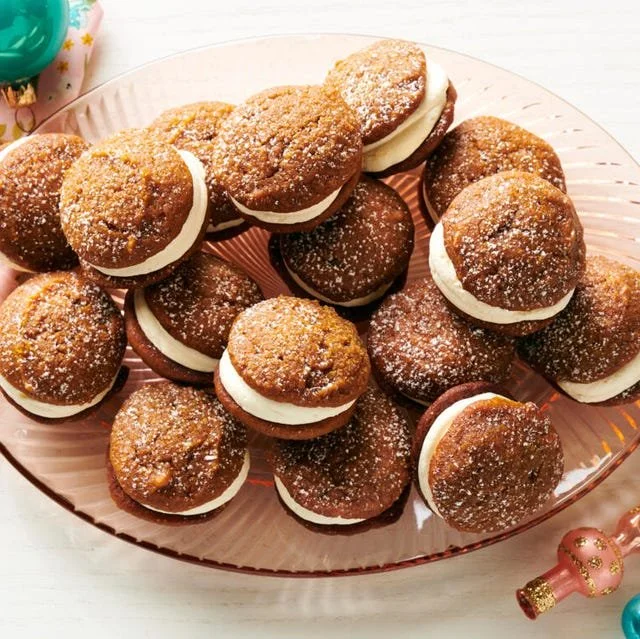 Delicious Pumpkin Whoopie Pies served on a wooden plate with autumn decorations.
