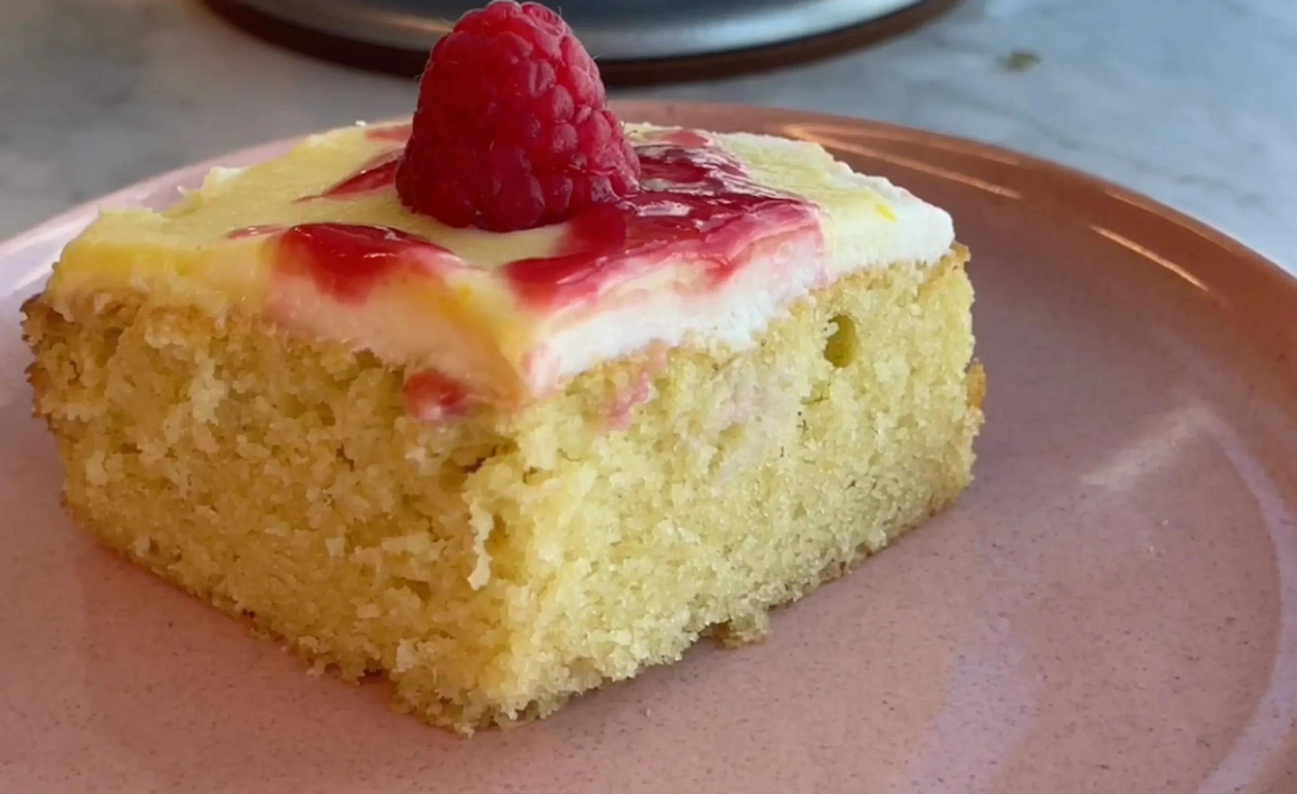 Raspberry Lemon Curd Snacking Cake topped with fresh raspberries.