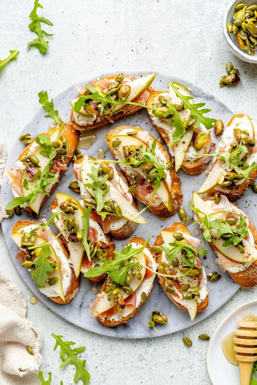 Ricotta and Pear Crostini with Pumpkin Seed Pistachio Crunch on a platter