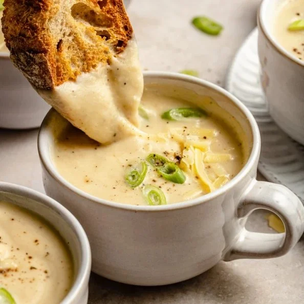 A bowl of roasted garlic cheddar cauliflower soup topped with fresh herbs