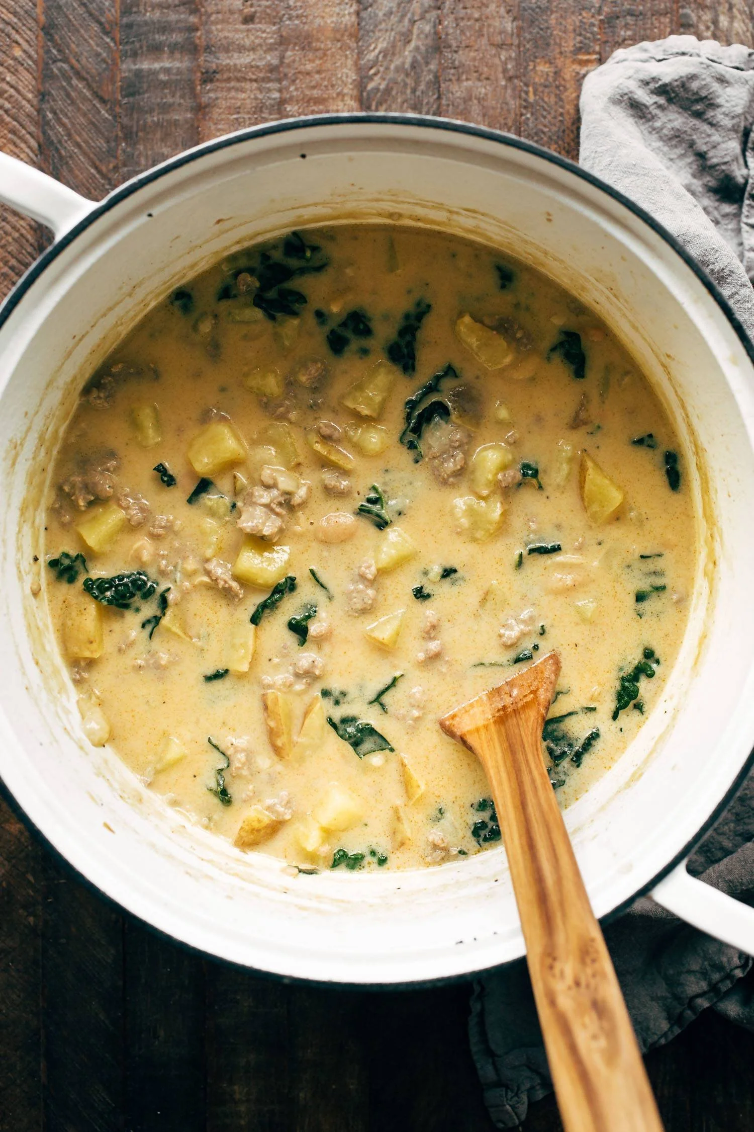 Sausage, kale, and white bean soup in a bowl garnished with herbs.