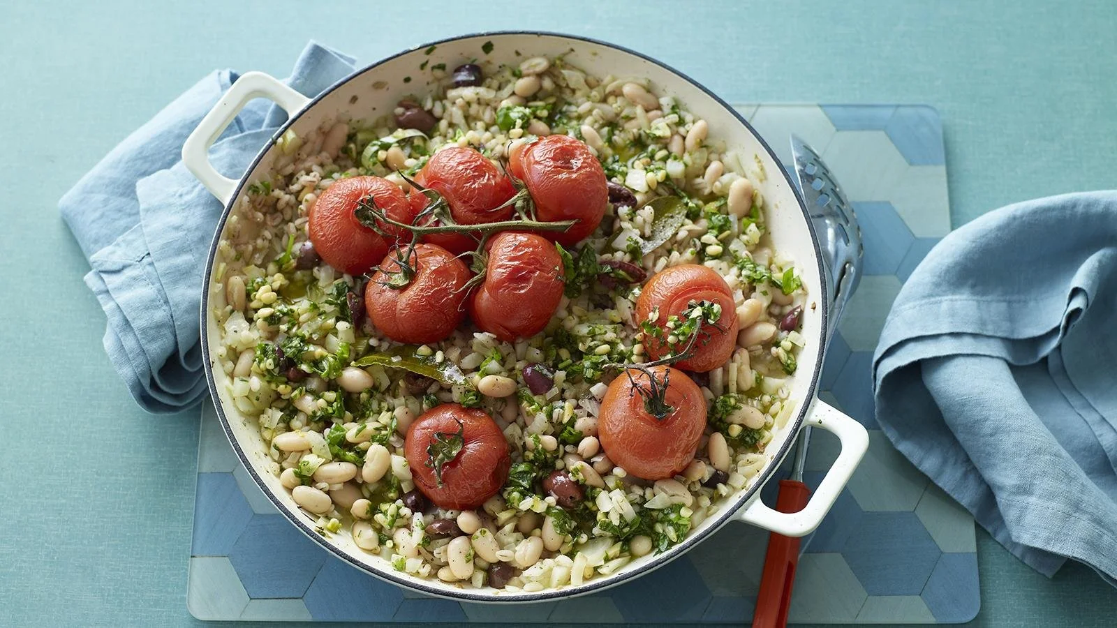 Bowl of slow-cooked tomato and fennel stew with pearl barley, garnished with herbs.