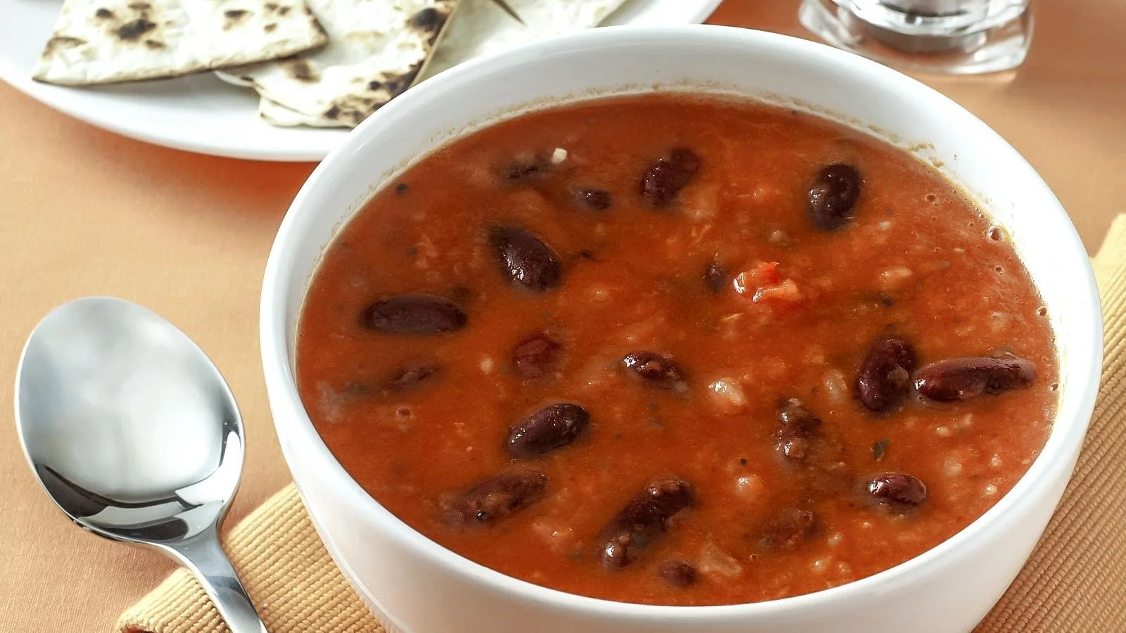 Bowl of Spicy Mexican Bean Soup garnished with fresh herbs and chili