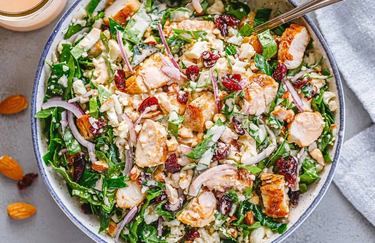 A colorful bowl of Spinach Chicken Salad with fresh vegetables and grilled chicken.