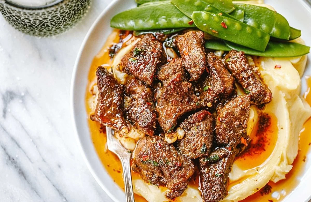 Juicy steak bites served with creamy mashed potatoes on a plate