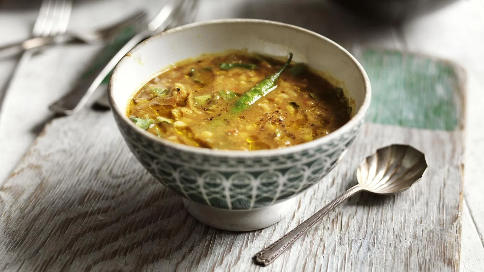 A bowl of Tarka Lentils garnished with spices and herbs, showcasing its vibrant colors.