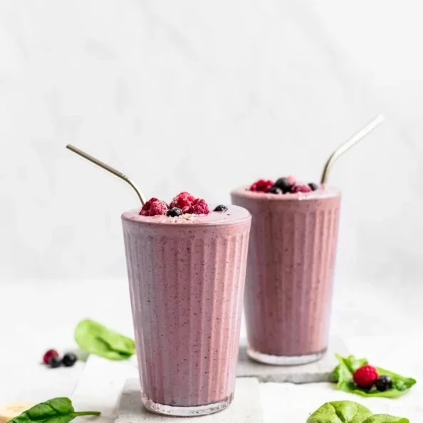 Delicious mixed berry smoothie in a glass topped with fresh berries